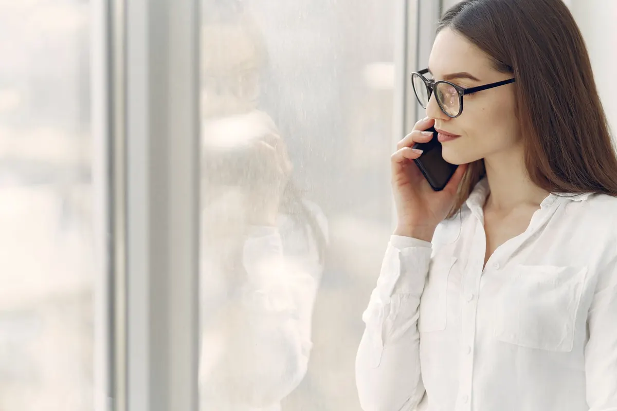 Femme au téléphone près d'une fenêtre, en conversation calme