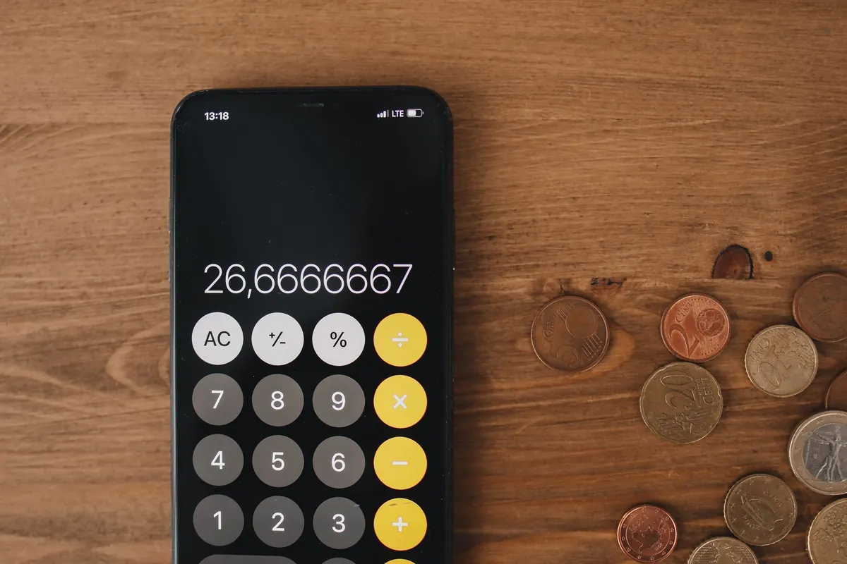 Calculatrice de smartphone posée entre des pièces de monnaie