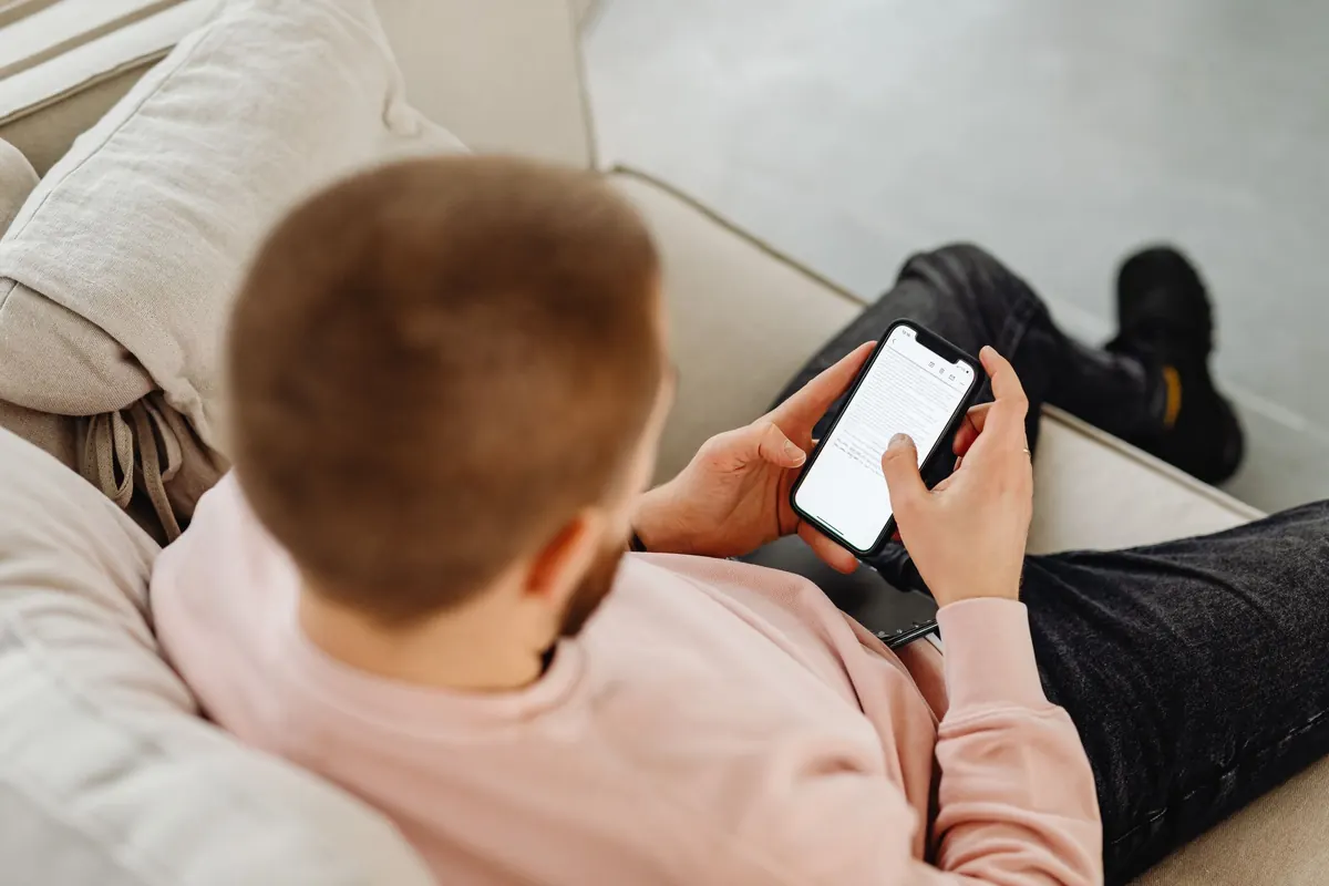 Homme allongé sur un canapé qui consulte son smartphone