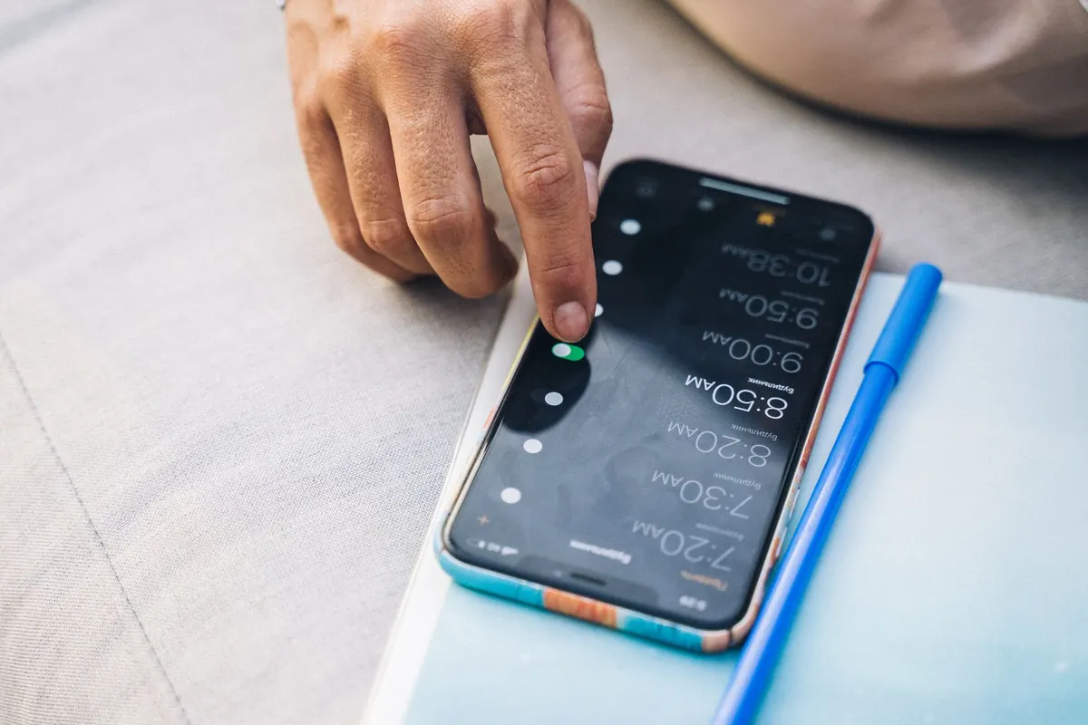 Doigt qui règle des horaires sur l'écran d'un smartphone posé sur un bureau