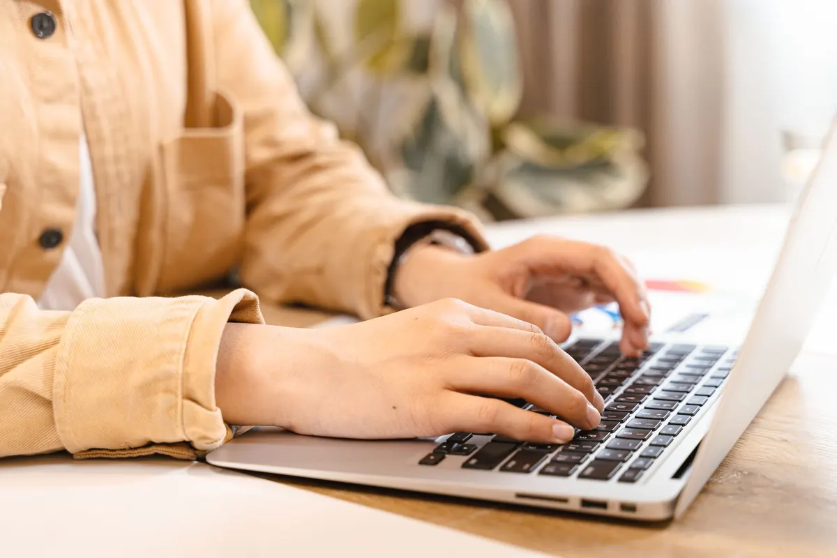 Mains d'un adulte qui saisit ses informations sur un ordinateur portable