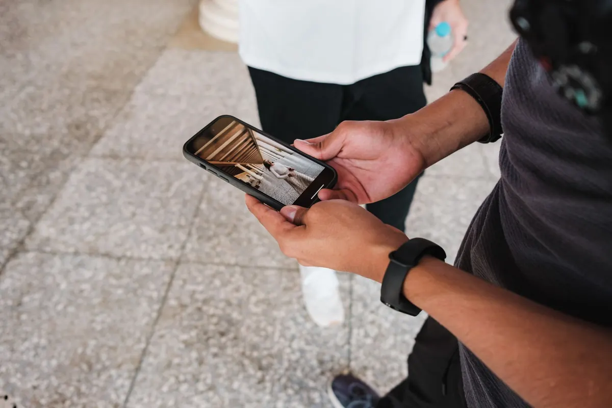 Mains d'un adulte qui tient un smartphone en extérieur