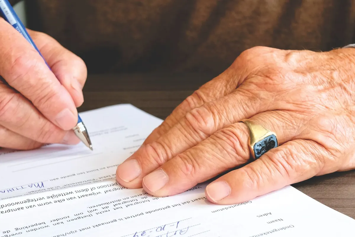 Main d'un adulte qui signe un formulaire au stylo