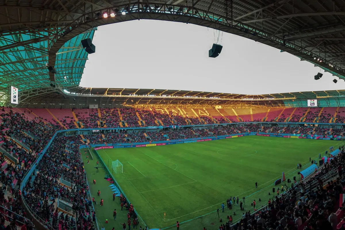 Stade de football vu depuis les tribunes avec la pelouse éclairée